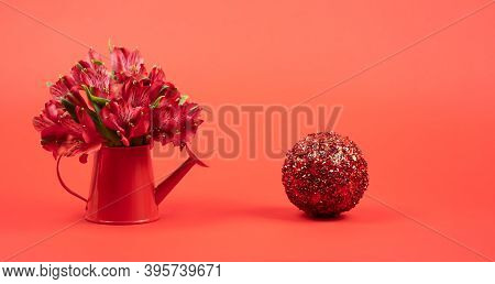 Mini Watering Can With Flowers On A Red Background And Shiny Apple On A Red Background. Copy Space F