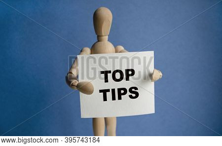 The Wooden Man Holds A White Sign With The Text Top Tips In His Hands. The Content Of The Lettering 