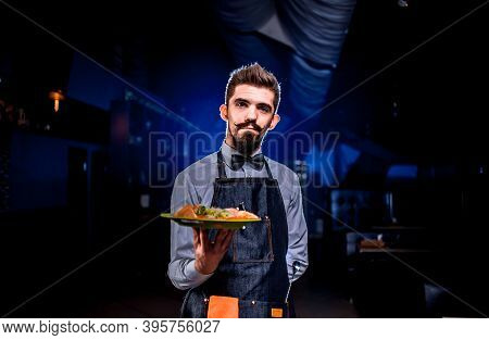 Charismatic Waiter Serves Plate With Prepared Dish In The Restaurant.