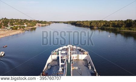 Aerial View Of Cargo Commercial Ship Sailing Down The River Surrounded By Green Forest On A Summer S