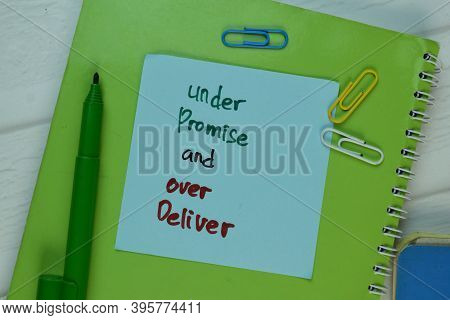 Under Promise And Over Deliver Write On Sticky Note Isolated On Wooden Table.