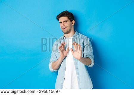 Displeased Man Refusing, Saying No And Cringe From Something Disgusting, Standing Over Blue Backgrou