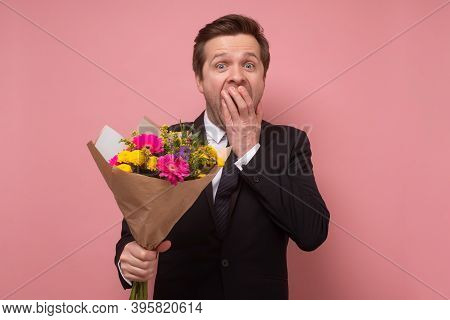 Smiling Man Holding A Bouquet Of Flowers Beong Shocked Or Surprise.