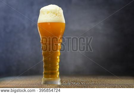 Weizen Beer On The Glass Table With Water Drops. Dark Background.