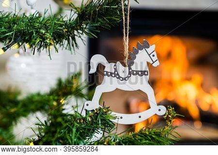 Wooden Christmas Decoration In The Shape Of White Horse With The Flame Of Fireplace In Background