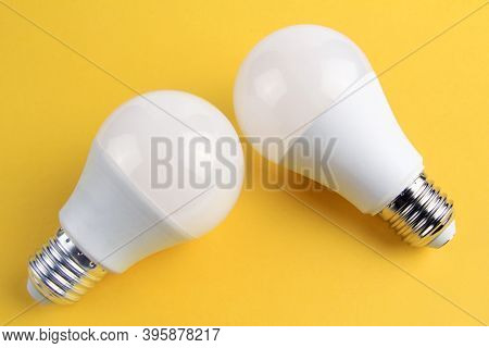 Two Electric Incandescent Lamps In White Matte Color On A Yellow Background.