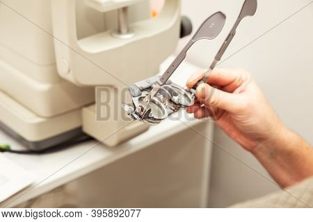Man's Hand Holds An Optometric Trial Frame For Diopter Adjustment. Ophthalmological Clinic, Vision E