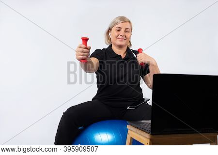 Senior Woman Doing Fitness Exercise Online, On A Itness Sword Holding Dumbbells.