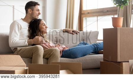 Couple Resting On Couch On Moving Day To New Home