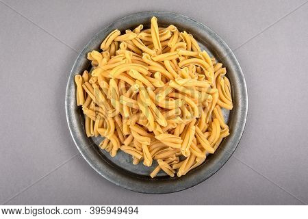Strozzapreti, Italian Pasta In Metal Plate On A Gray Table