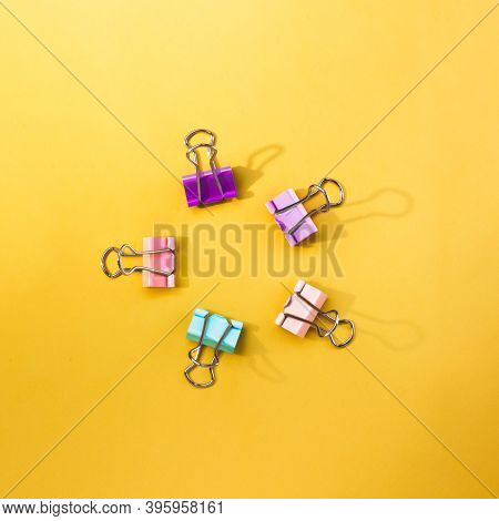 Five Colorful Paper Clips Forming Circle On A Yellow Backdrop. Good Stationery Backgrop With Space F
