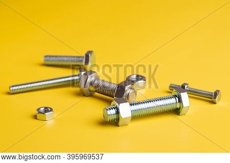 Nuts And Bolts. Close-up Of Nut Bolts On Yellow Background. Fastening Tool Bolts And Nuts.