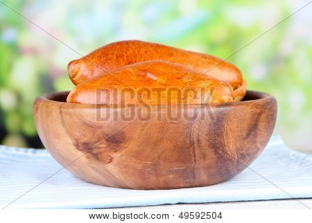 Empanadillas al horno frescos, en un recipiente de madera, en la mesa de madera, sobre fondo brillante