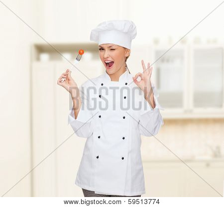 cooking and food concept - smiling female chef, cook or baker with fork and tomato showing ok sign