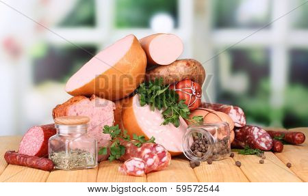 Lot of different sausages on wooden table on window background