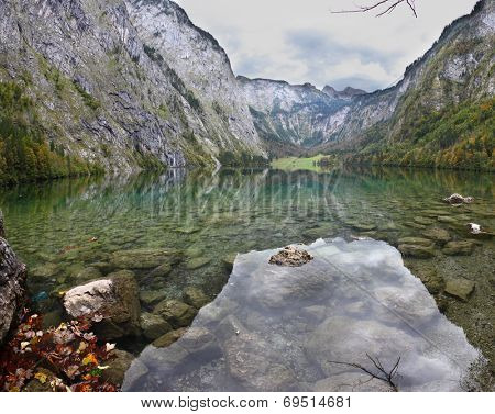 Magic reflection in German lake Koenigssee. Cloudy day on the lake. Clouds and mountains reflected in the mirrored surface of the water
