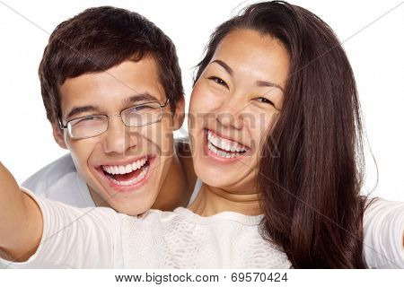 Close-up portrait of young smiling interracial couple taking selfie isolated on white background