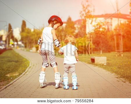 two little sisters to roller skate on the street, back view