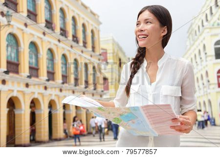 Tourist holding travel map in Macau. Woman visiting Macau, China for sightseeing looking for directions at tourists map smiling happy on Senado Square or Senate Square.