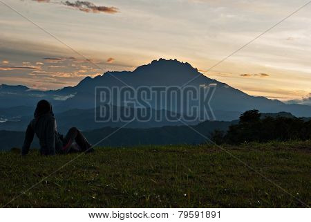 Unidentified Woman Taking A Rest On The Grass With Mount Kinabalu As Background