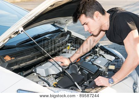 Handsome young man trying to repair a car engine