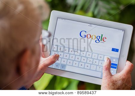 Paris, France - April 27, 2015: Senior Woman Using Tablet With Google Search Home Page On A Ipad Scr
