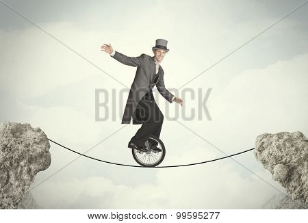 Brave business man riding an mono cycle between cliffs concept