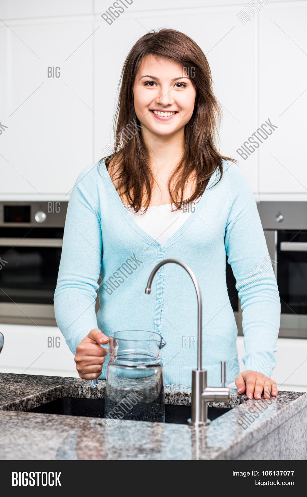 Девушка наливает воду. Девушка пьет воду из под крана. Девушка пьет воду на кухне. Вода питьевая в стакане. Девушка пьет из кувшина.