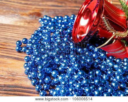 Blue Beads With Red Christmas Bell On Old Wood Background