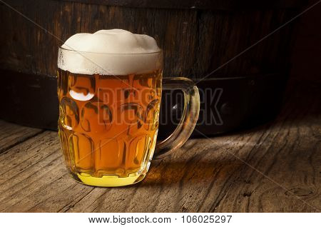 Still life: old wooden barrel of beer, glass of beer and wheat on the table in the cellar.