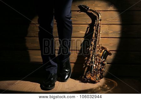 The musician with sax on wooden background, close up