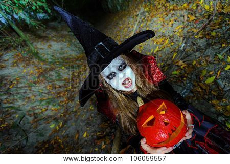 Little Girl Dressed In Witch Costume In Halloween Forest