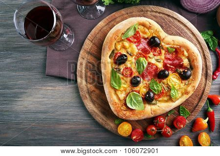 Heart shaped pizza served on wooden table, closeup