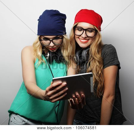 two hipster girls friends use digital tablet, studio shot over gray vackground