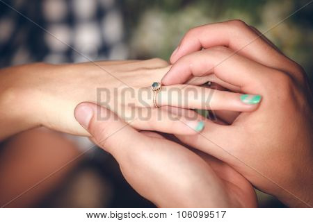 Man placing engagement ring on the finger of his fiance