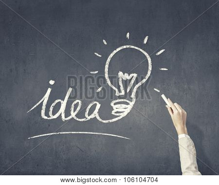 Human hand darwing light bulb as idea concept with chalk