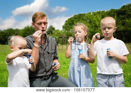 Elder brother teaches the younger brothers and sister blowing bubbles