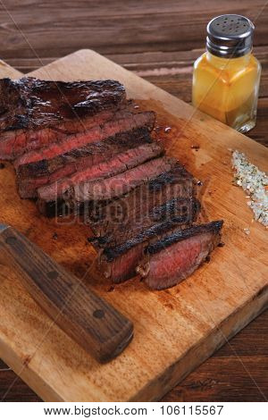 fresh roast red beef meat fillet mignon cutted on wooden plate with vintage fork many different kinds of dry spice over table