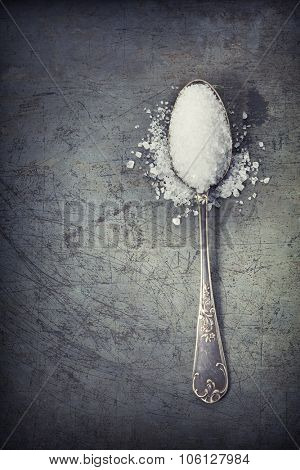 silver spoon filled with salt on rustick background