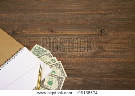 Brown Wood Table With Notebook, Money  And Gold Ink Pen