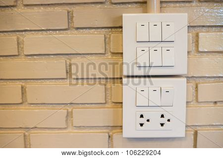 Dimmer Switch And Light Switch On Switchboard.over  Brick Wall