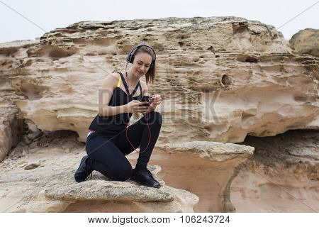 Attractive fitness woman choosing song in play list for listen to music in headphones