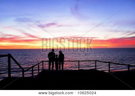 Familien se solnedgangen på stranden
