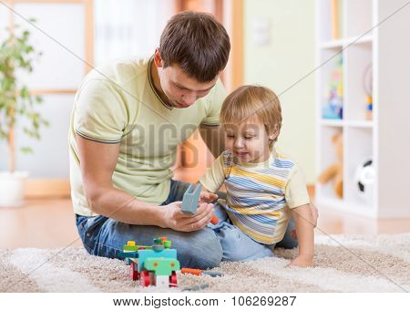 Child boy and his father repair toy car at home