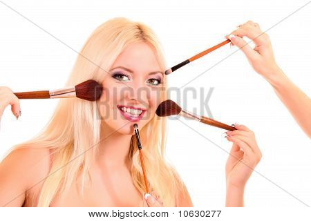 Giovane e bella donna bionda con molti pennelli su bianco e luminoso make-up