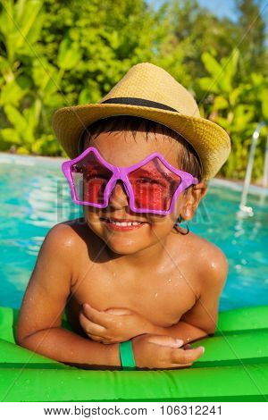 Cute boy in star-shaped sunglasses on green airbed