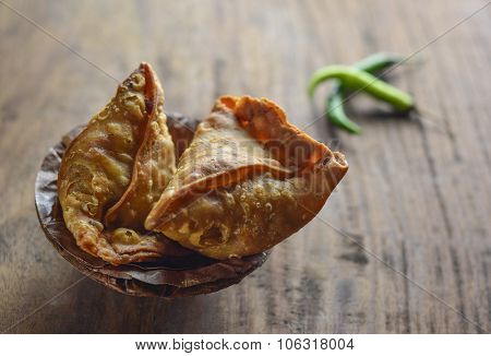 Popular indian street food - Punjabi Samosa in an earthen bowl with green chilies.