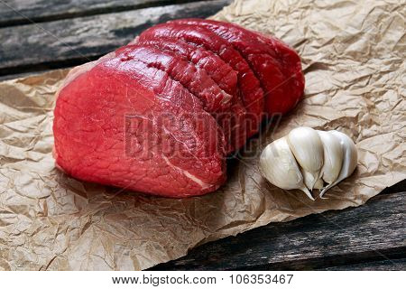 A Pieces Of Fresh Meat, Beef Slab On Crumpled Paper On Old Wooden Table. Ready To Cook.