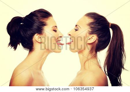Two attractive women with make up showing their tongs.
