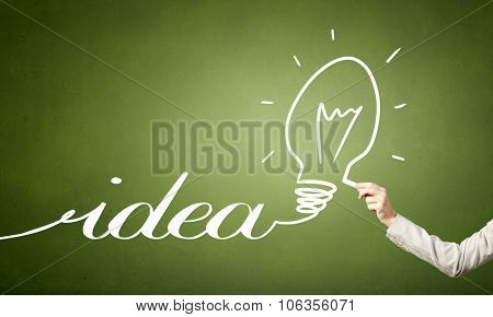 Human hand darwing light bulb as idea concept with chalk
